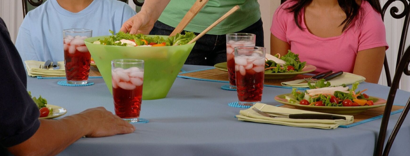 Saved money by cooking in hospital. Two parents and two children, sitting at a dinner table with a home prepared salad.
