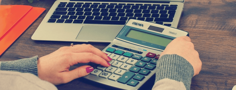 woman sitting at her computer with a calculator working out how to save money