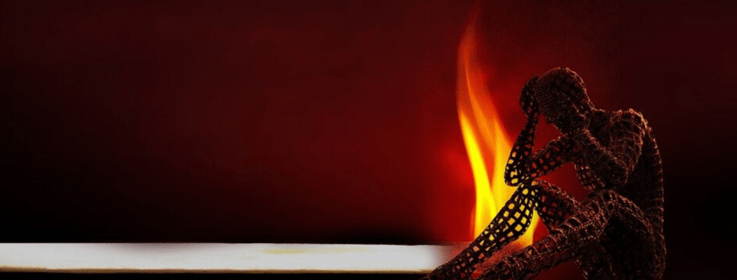 Candle burning close to the silhouetted wire frame outline of a person - perhaps experiencing caregiver burnout