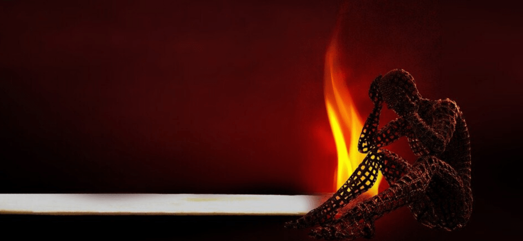 Candle burning close to the silhouetted wire frame outline of a person - perhaps experiencing caregiver burnout